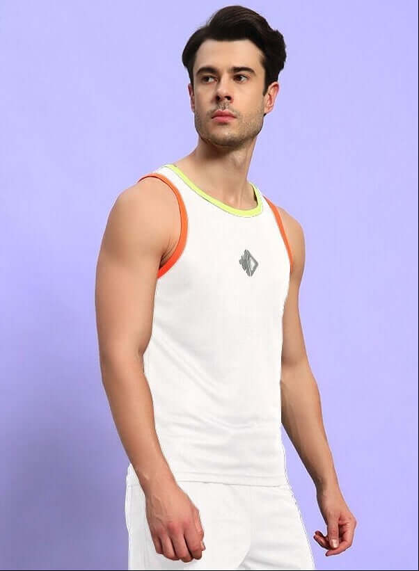 Man wearing a white athletic tank top with orange and green trim, standing against a purple background.