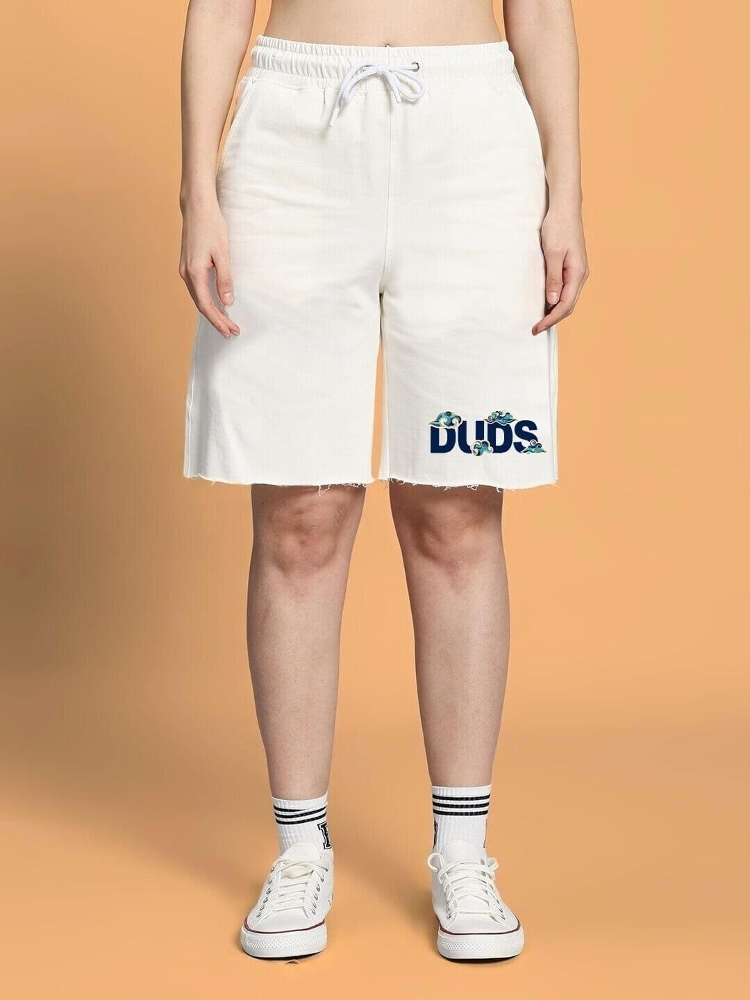 Model wearing WOMEN CLOUD PRINTED CO-ORD SET OFF WHITE shorts with cloud designs, showcasing casual style on an orange background.