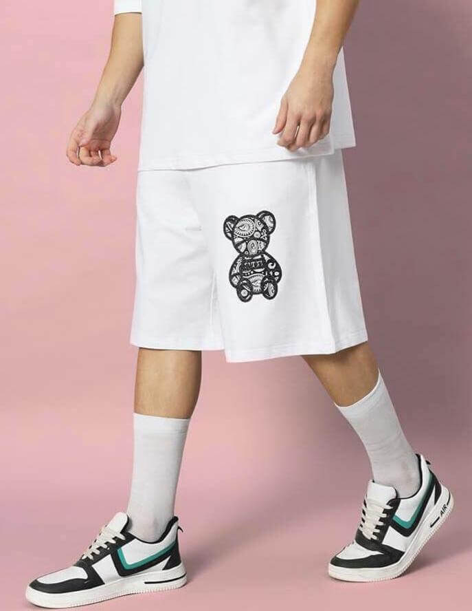 Person wearing SHIMMY REGULAR FIT SHORTS WHITE with bear graphic on pink background.