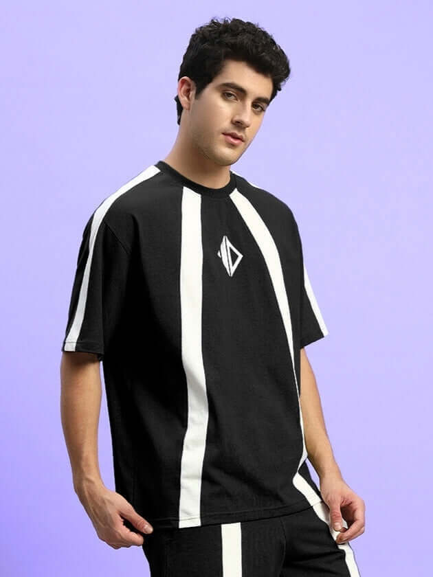 Man wearing WIDELINE OVER-SIZED T-SHIRT BLACK with white stripes in a casual streetwear style.