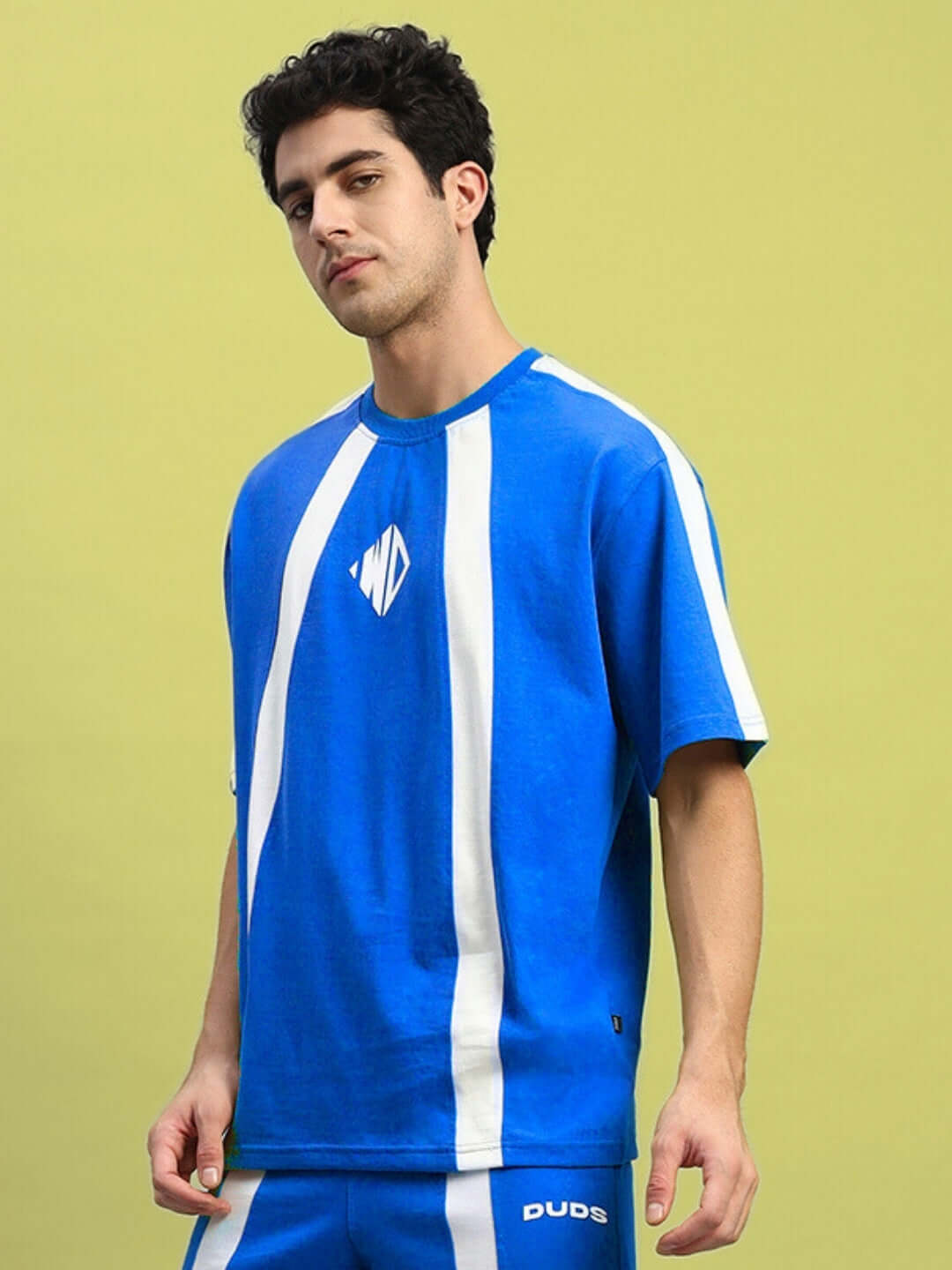 Model wearing WIDELINE OVER-SIZED T-SHIRT ROYAL BLUE with white stripes, showcasing streetwear fashion and relaxed fit.