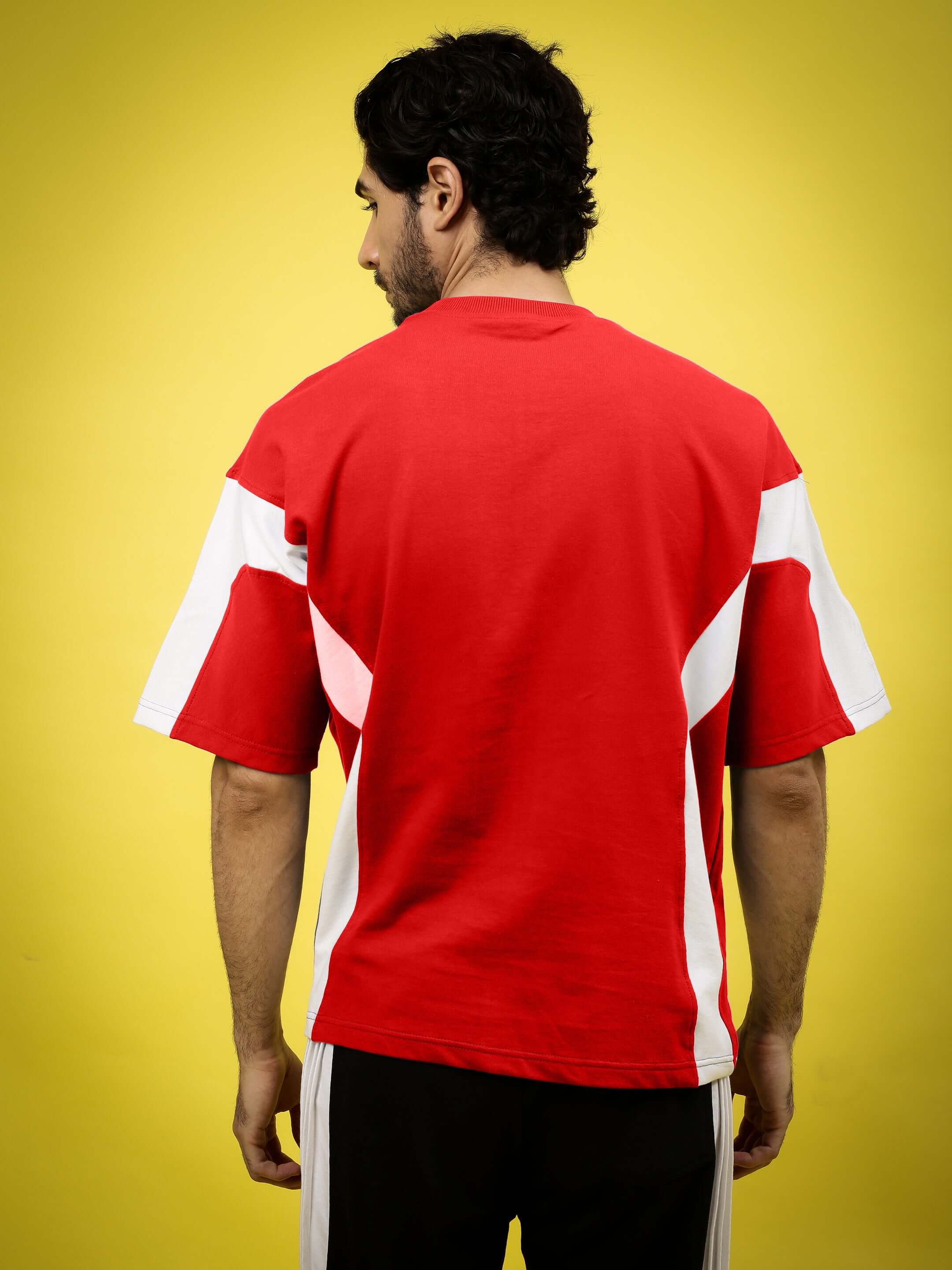 Man wearing WILD FORCE over-sized red-white t-shirt made of heavy gauge fabric with a bright yellow backdrop.