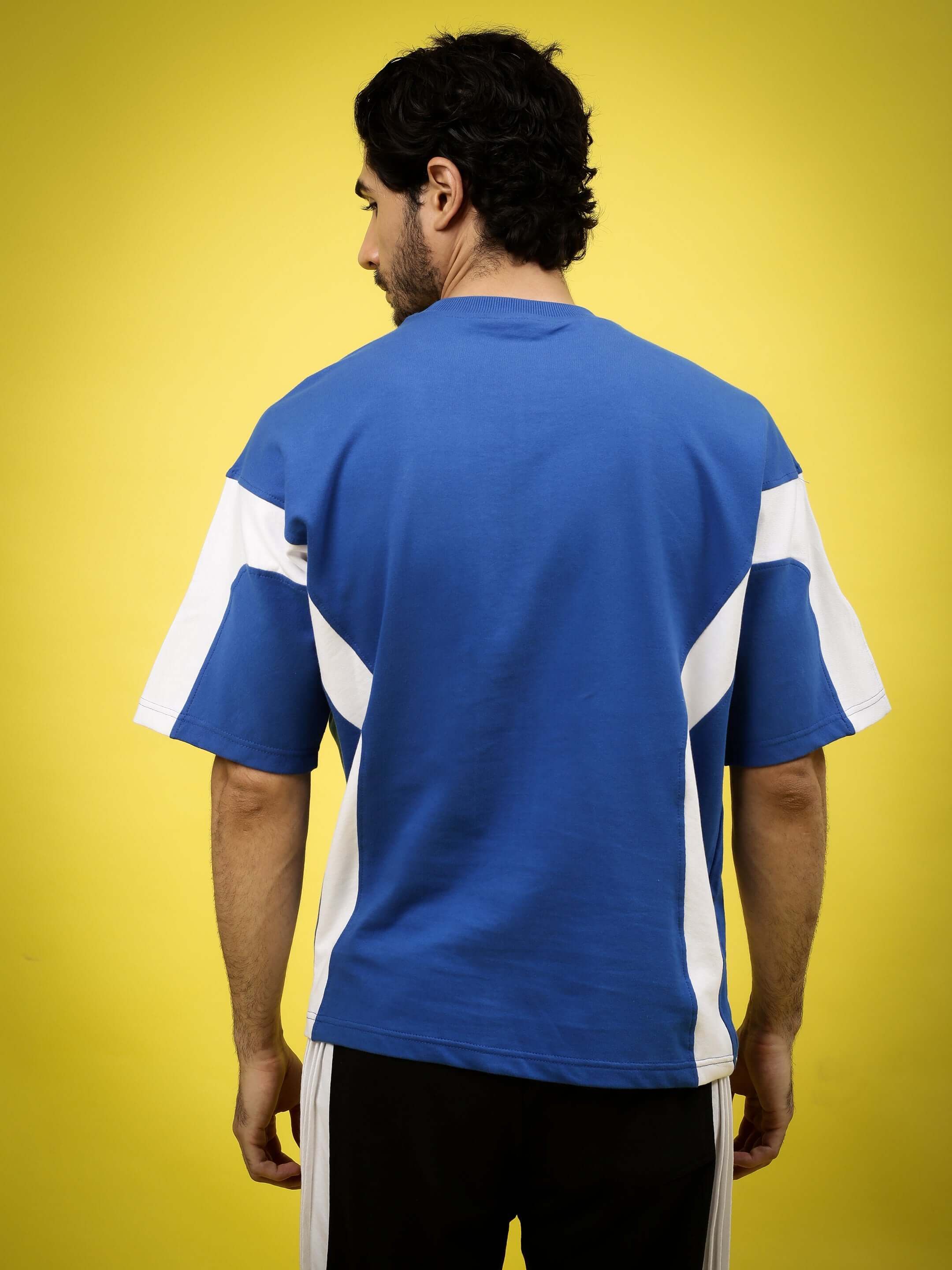 Model wearing WILD FORCE oversized T-shirt in royal blue and white, made from premium cotton French terry, back view.