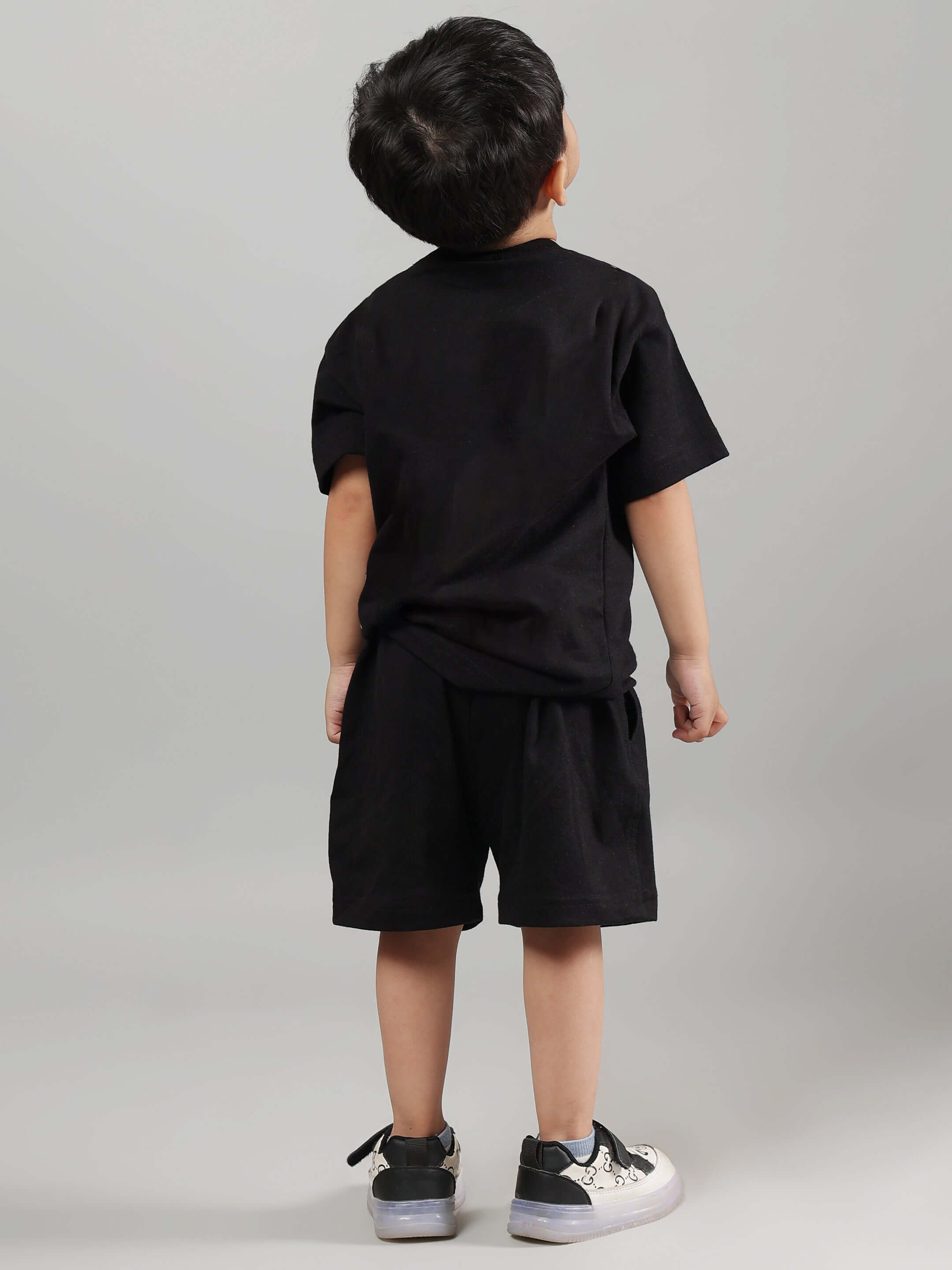 Child wearing black WIN DAY T-shirt and shorts set, showcasing rear view on a neutral background.