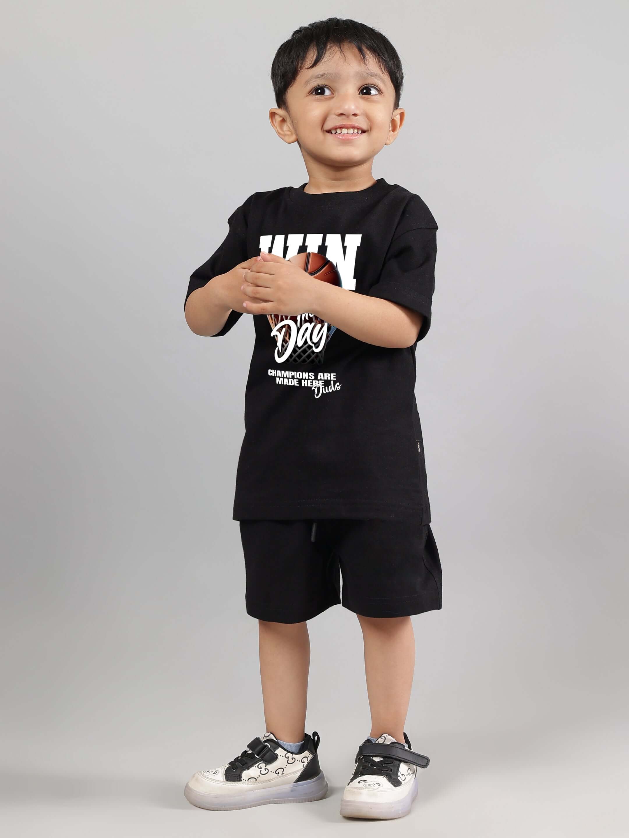 Young boy wearing a black WIN DAY T-shirt, smiling against a gray background, showcasing kids' casual fashion