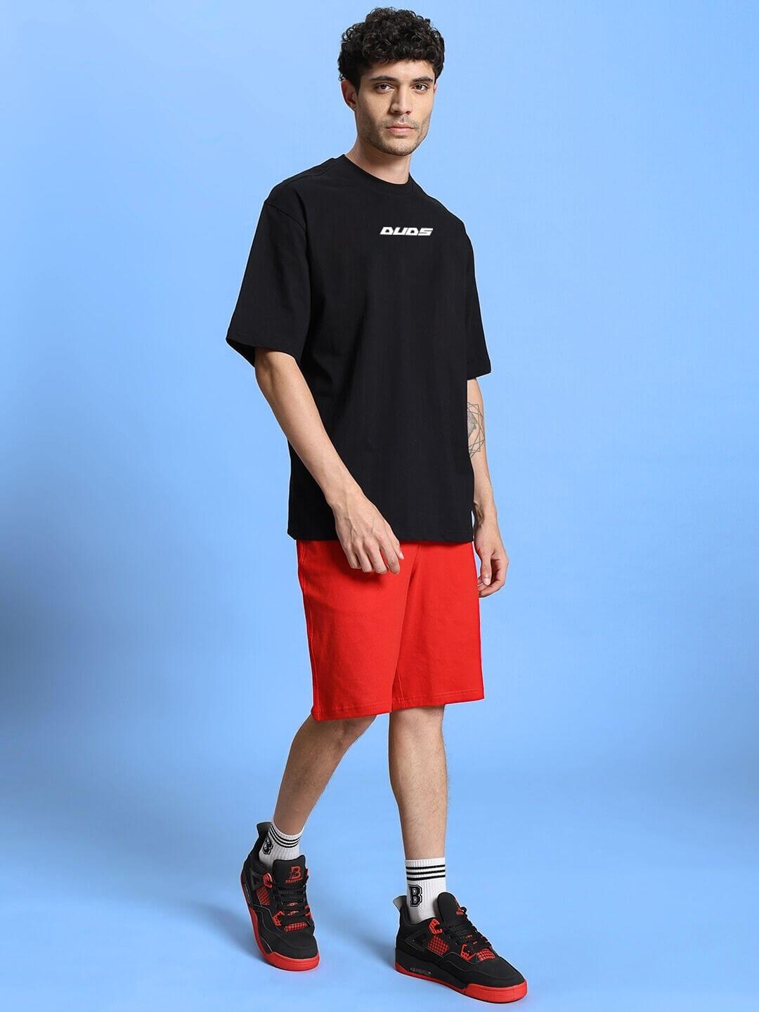 Model wearing WINGED WARRIOR PRINTED OVERSIZED CO-ORD SET BLACK RED with black t-shirt and red shorts, showcasing street-style fashion.