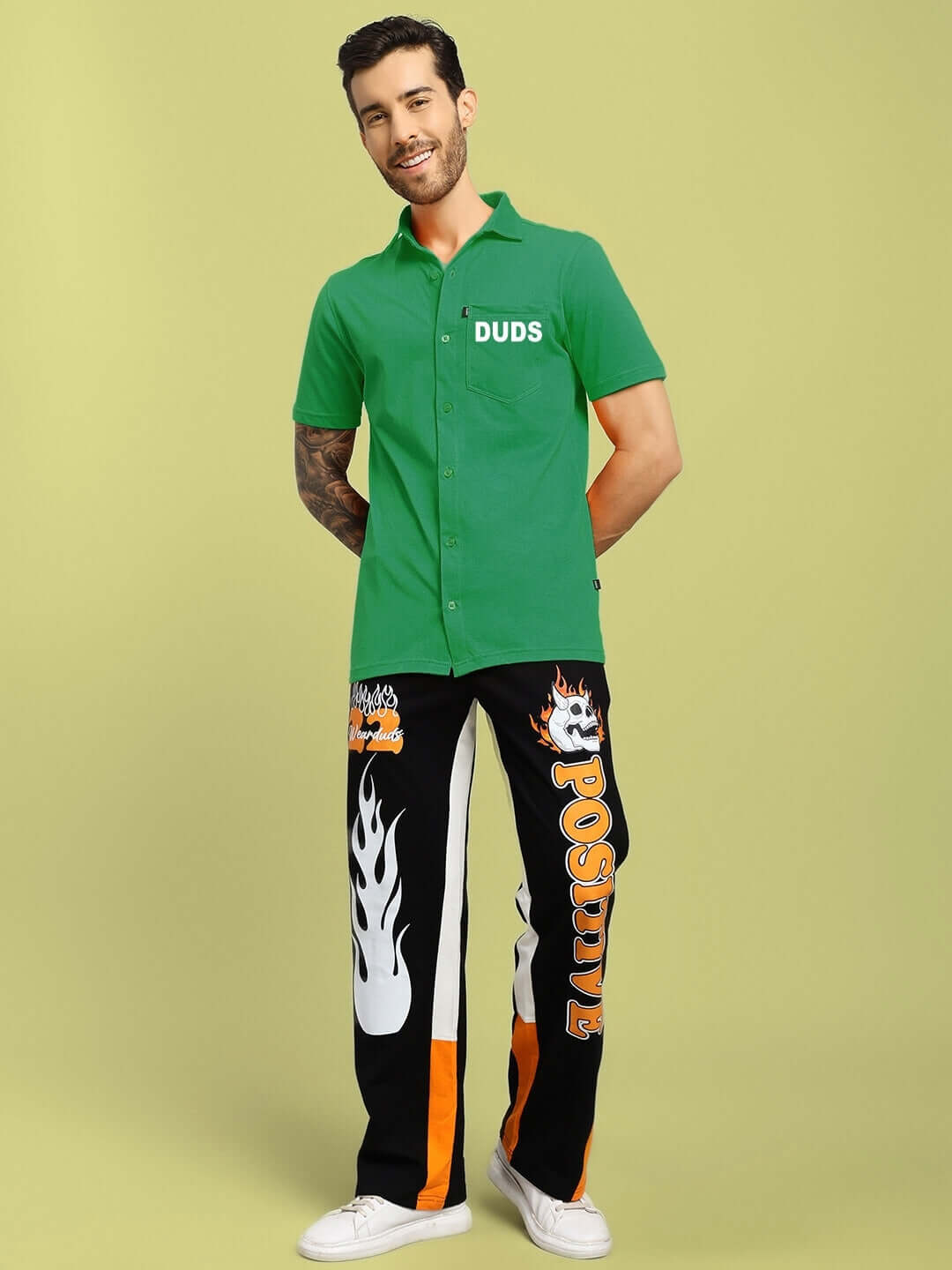 Man wearing green regular fit wings tee shirt by DUDS with customized flame-patterned pants against a light green background.