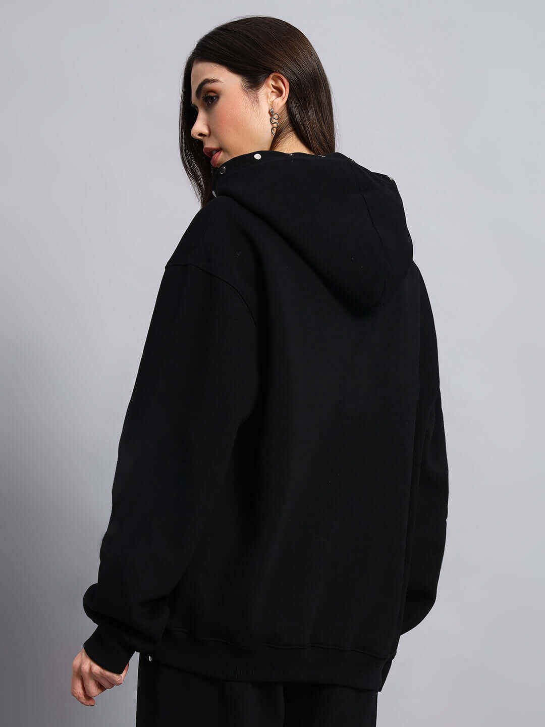 Woman wearing WOMEN RIGID FLEECE HOODIE BLACK from the back, showcasing comfortable fit and design.