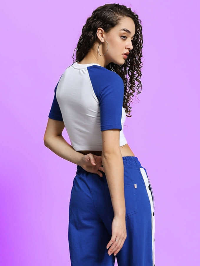 Model wearing Women's Achorm Crop-Top in White-Blue made from premium cotton fabric, showcasing back design against purple backdrop.