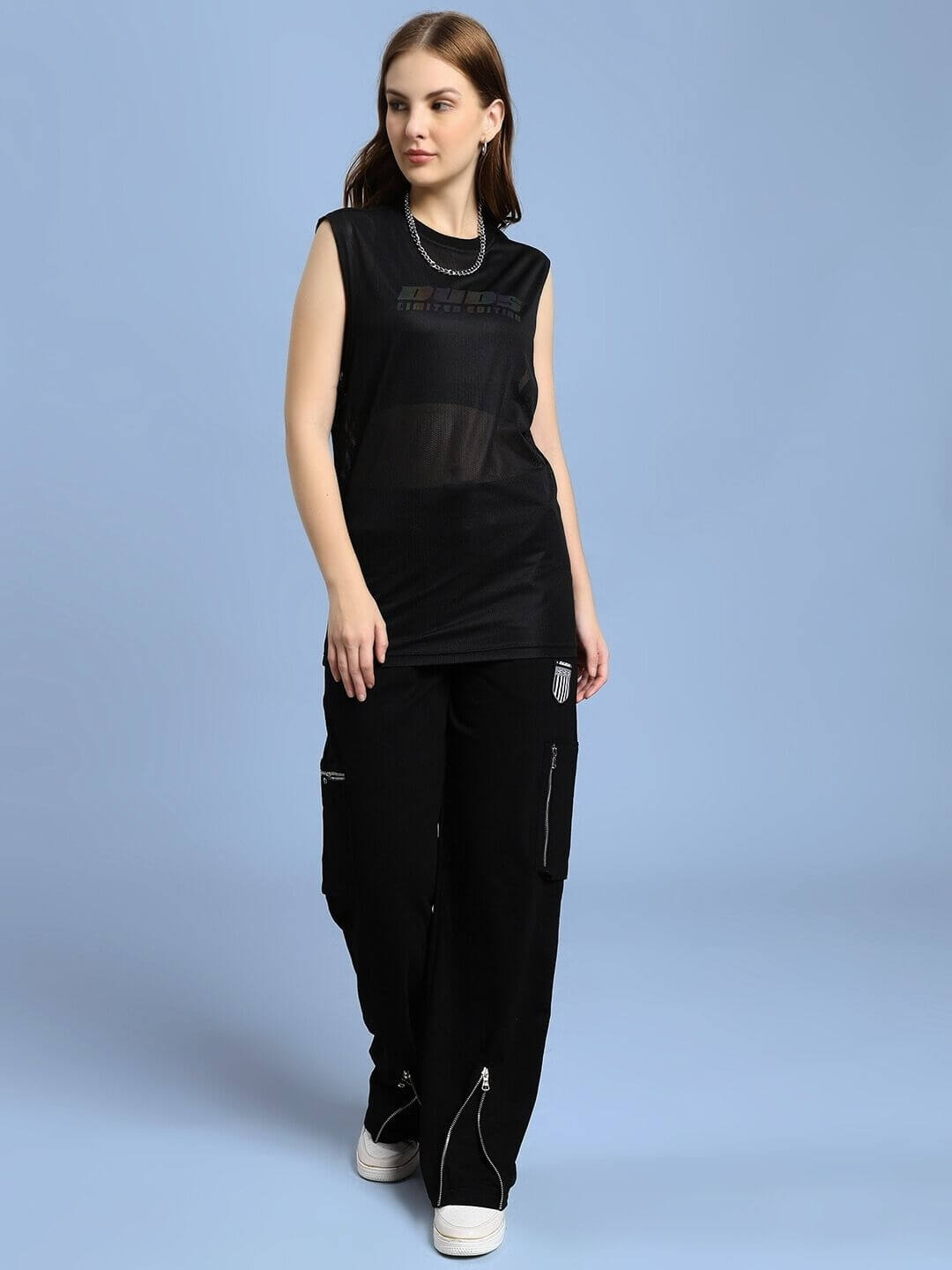 Model wearing WOMEN AIR-FLOW REGULAR FIT T-SHIRT BLACK with cargo pants against blue background.