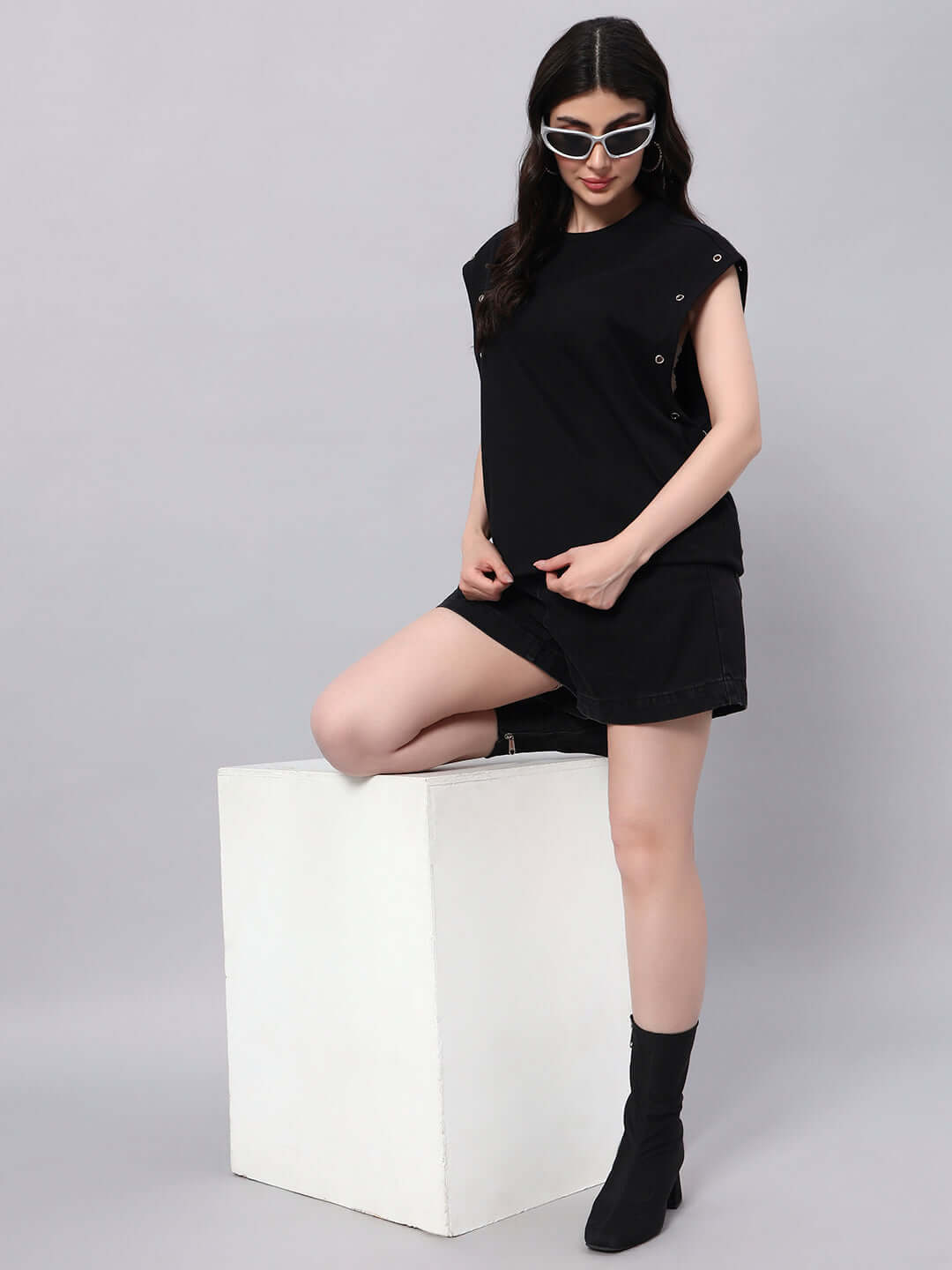 Model wearing WOMENS ALVEN OVERSIZED T-SHIRT BLACK, styled with trendy sunglasses and black boots, showcasing contemporary fashion.