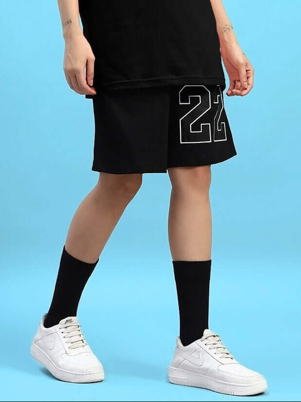 Women's Amiga Regular Fit Black Shorts featuring custom fit option and sporty design, worn with black socks and white sneakers.