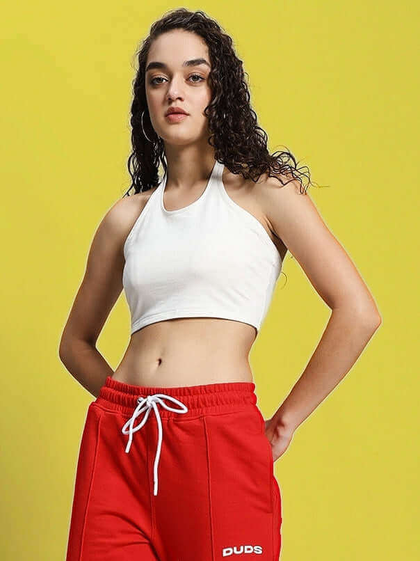 Woman wearing off white crop top with red athletic pants on yellow background