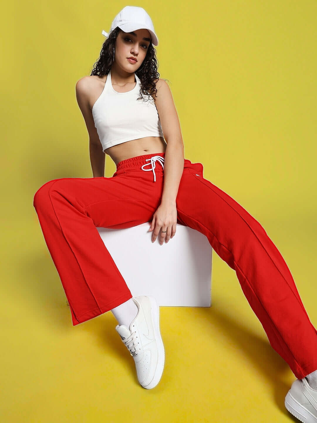 Model wearing WOMEN'S ANISSA CROP TOP OFF WHITE with red pants, posing against a yellow background.