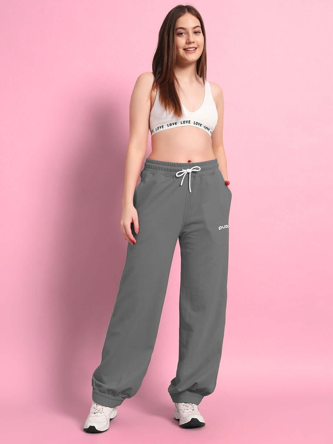 Model wearing WOMENS AUSTRIAN RELAXED-FIT JOGGERS GREY, showcasing comfortable and stylish design against a pink backdrop.