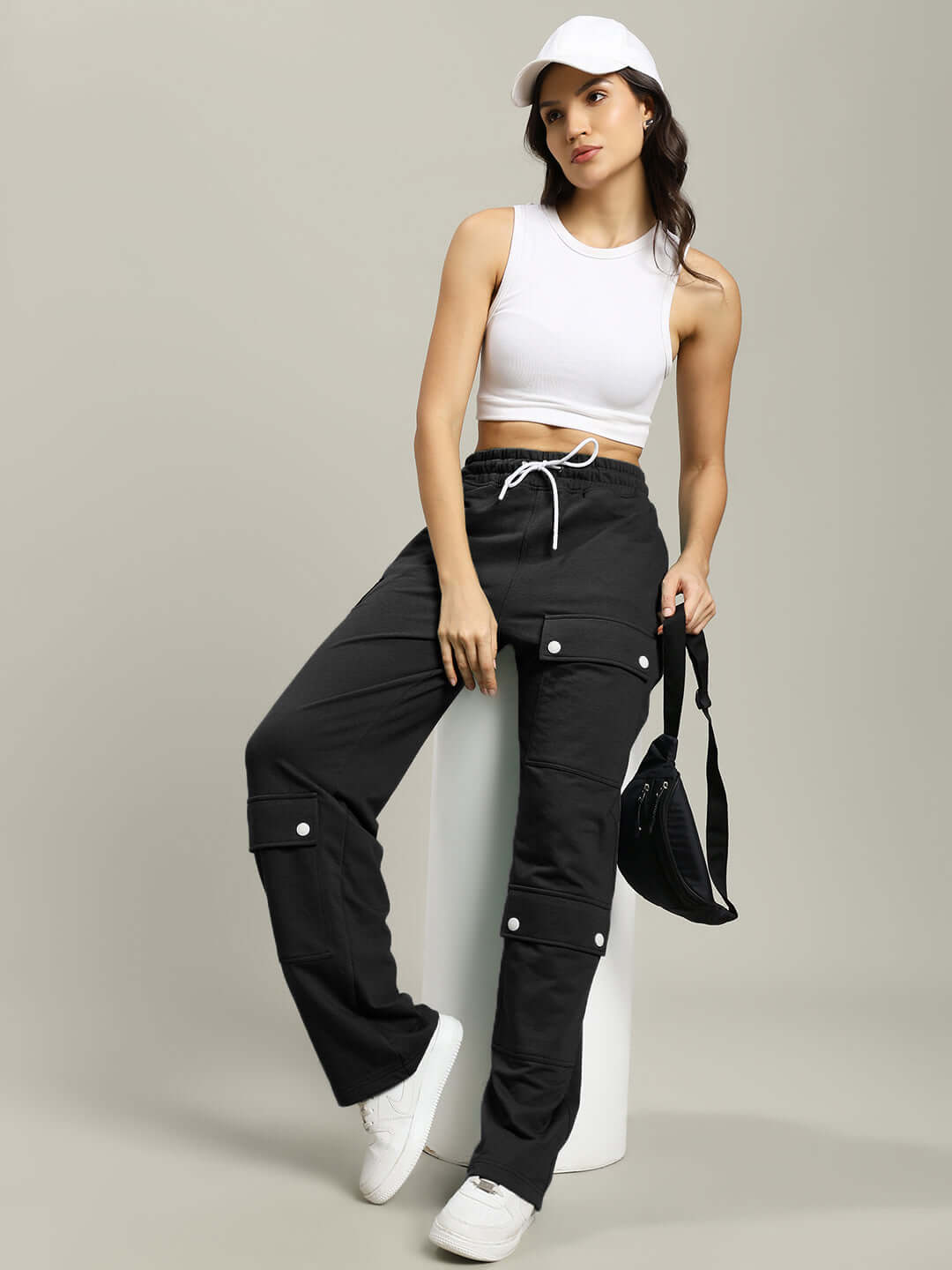 Woman wearing Women's Awesome Flap Pocket Baggy Jogger in black paired with white top and cap, showcasing stylish casual wear.