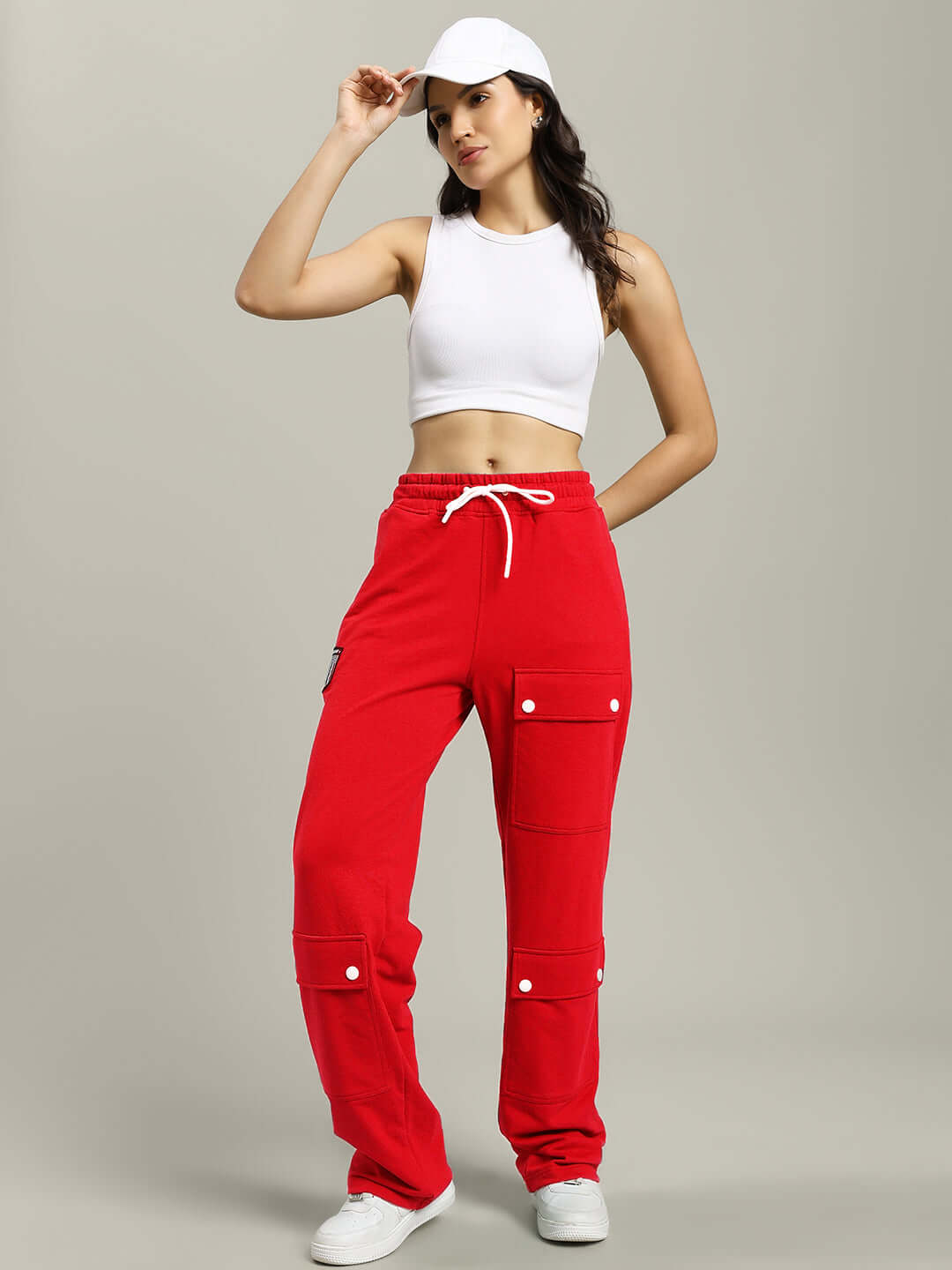 Woman wearing WOMENS AWESOME FLAP POCKET BAGGY JOGGER RED with white top and cap, showcasing streetwear style and flap pockets.