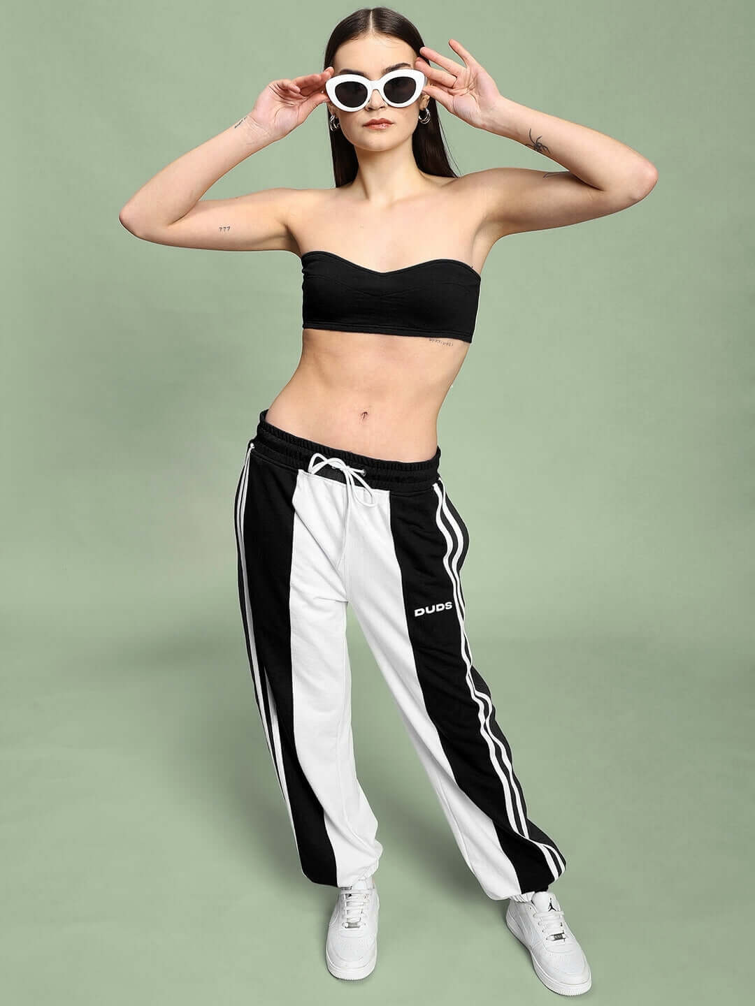 Woman wearing WOMEN'S BALMY RELAXED FIT JOGGER WHITE BLACK with sunglasses and tube top, showcasing a casual chic style.