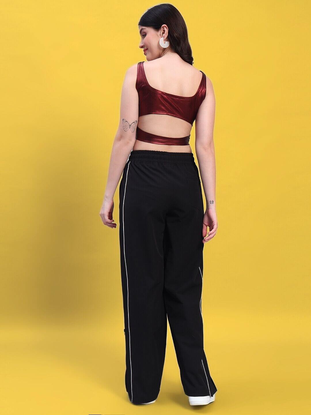 Woman wearing maroon-black co-ord set by Color By Colours, featuring metallic top and polyester joggers, on yellow background.