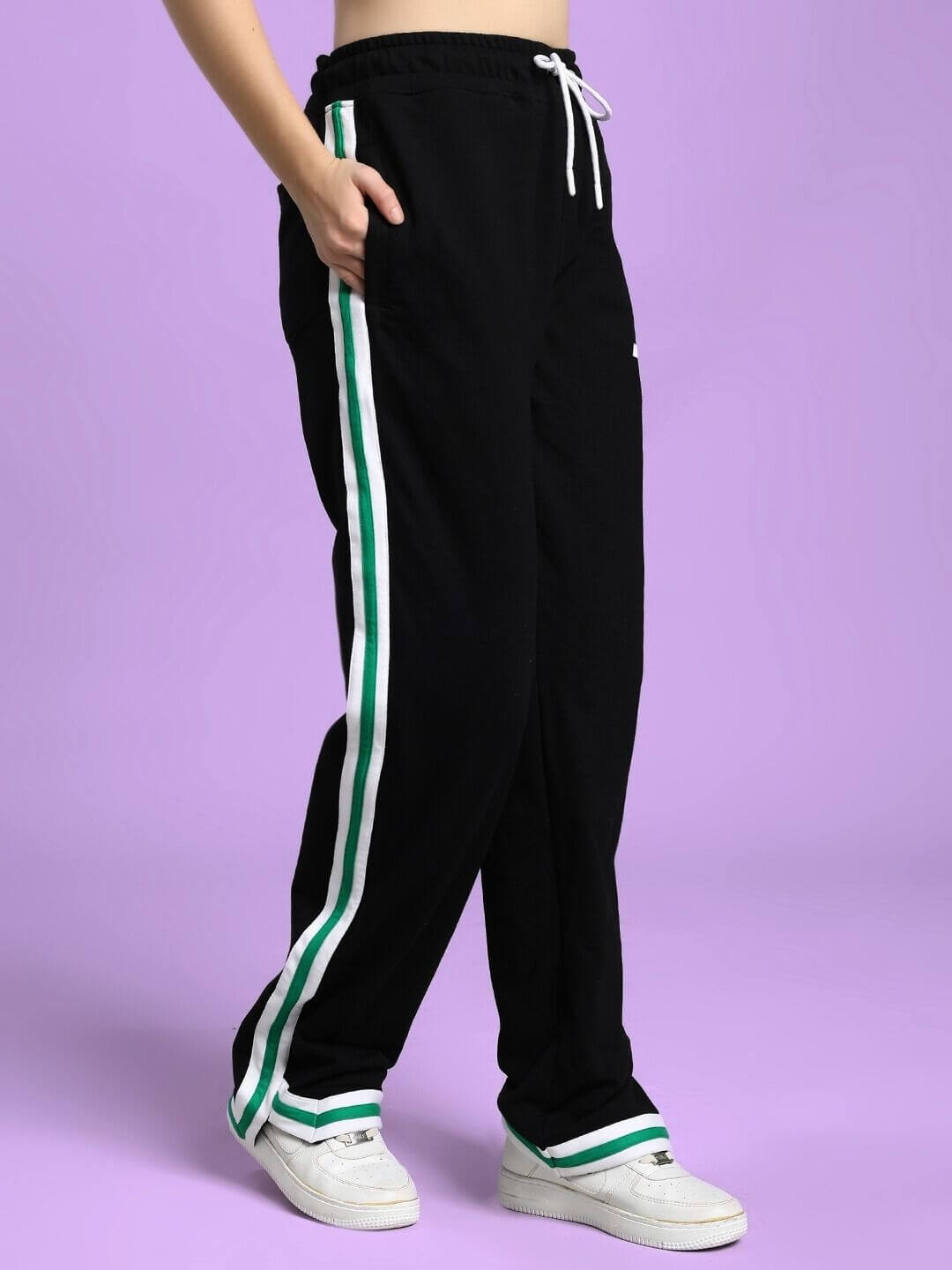 WOMEN'S VELO GREEN STRIPE RELAXED FIT JOGGER BLACK with white sneakers, showcasing elongated leg design and sporty green accents.