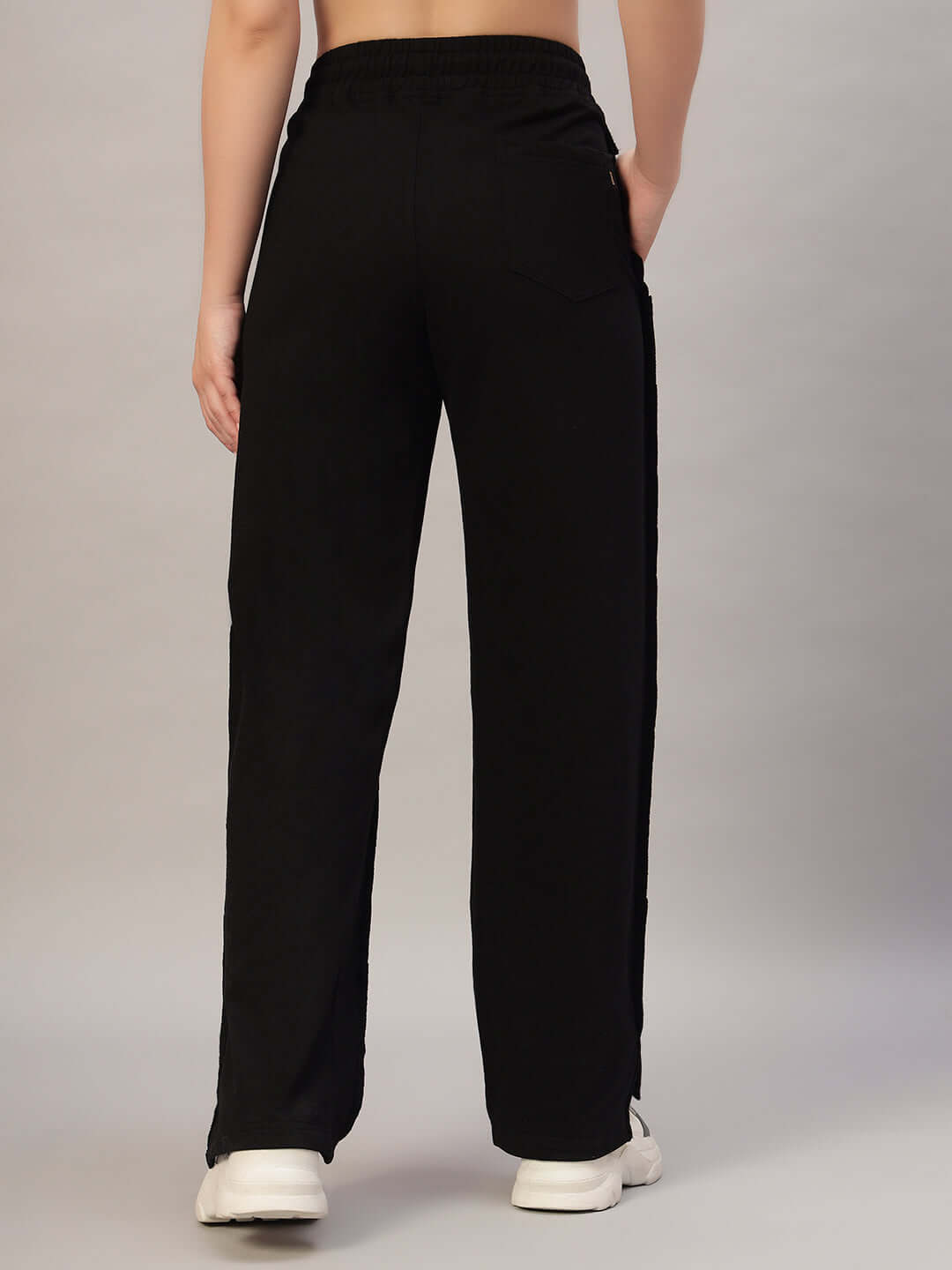 Back view of women's black joggers with side slit, showcasing elastic waistband and casual fit.