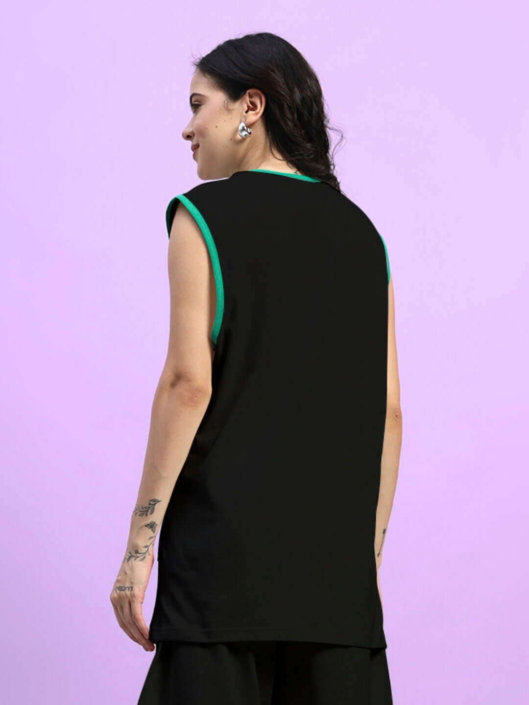 Back view of a woman wearing a black oversized T-shirt with green trim on a purple background, showcasing a relaxed summer style.