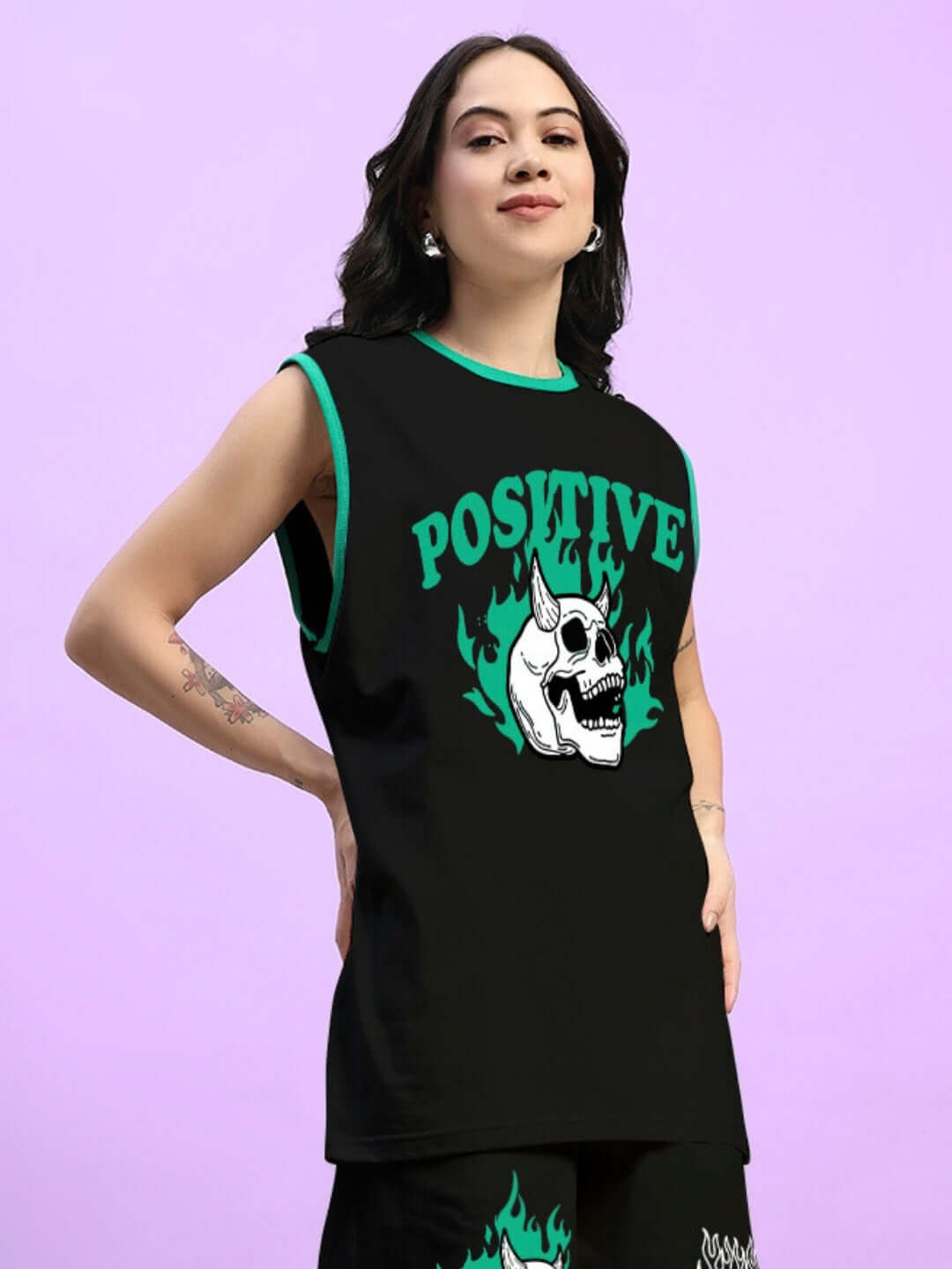 Woman wearing a black oversized t-shirt with 'Positive' text and skull design, showcasing a trendy summer look on a pastel purple background.