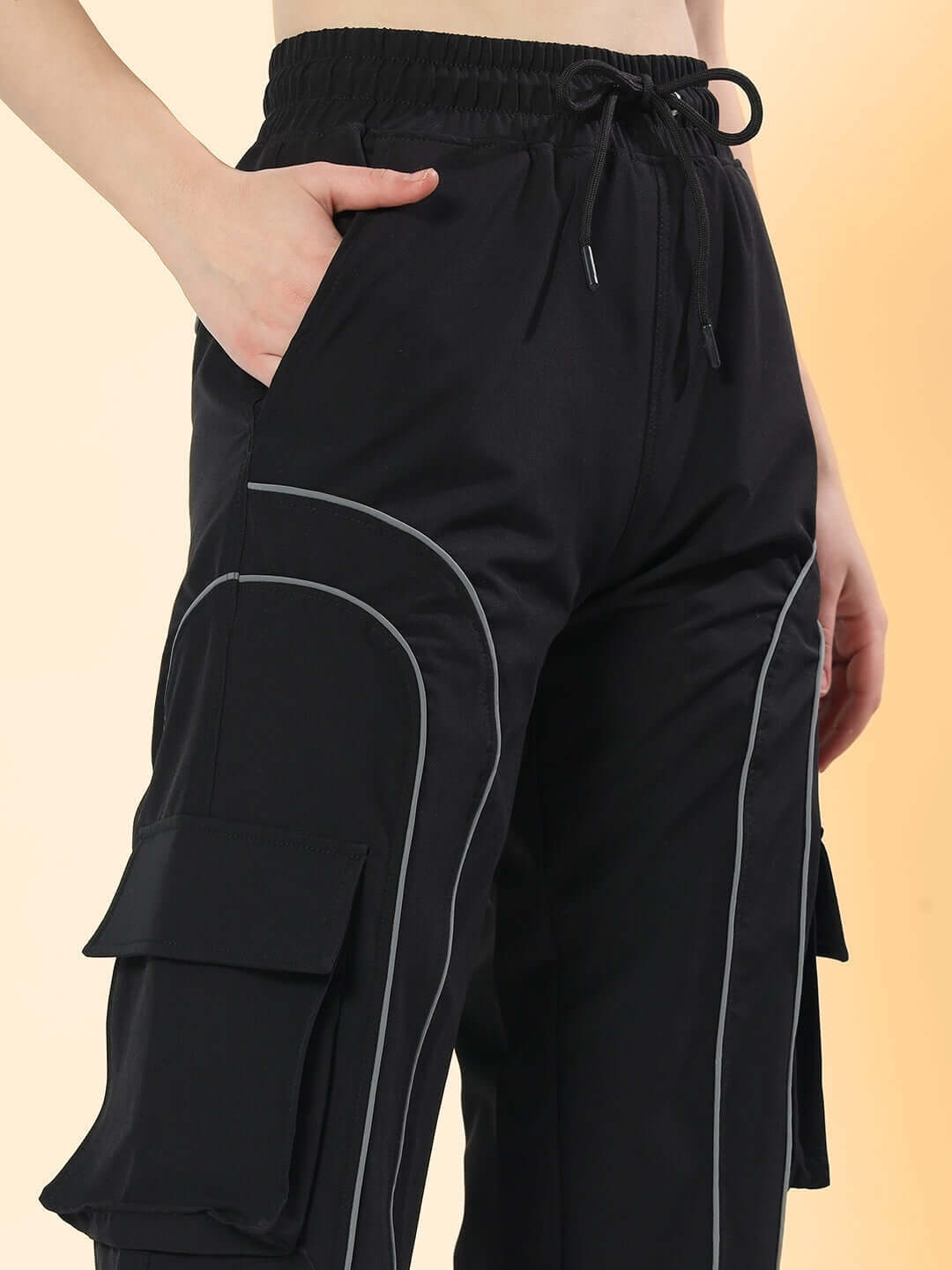 Close-up of black women's ray reflector parachute cargo pants with pocket details.