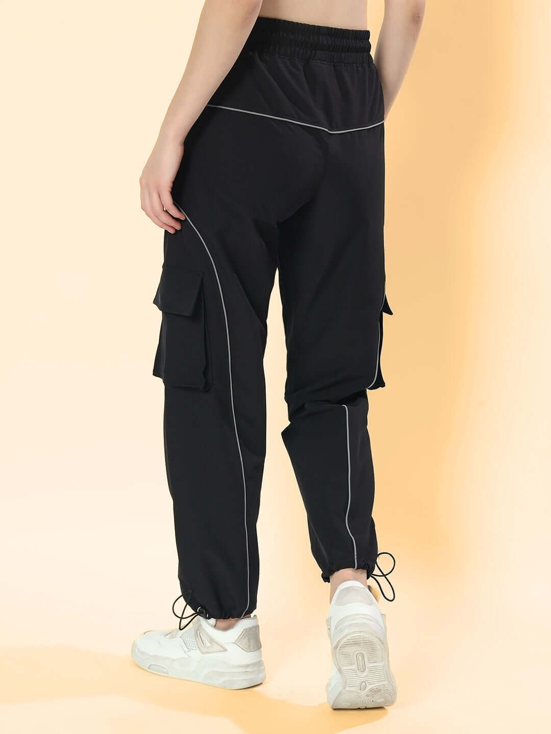 Back view of women's black Ray Reflector Parachute Cargo Pants featuring custom fit option, shown with casual white sneakers.