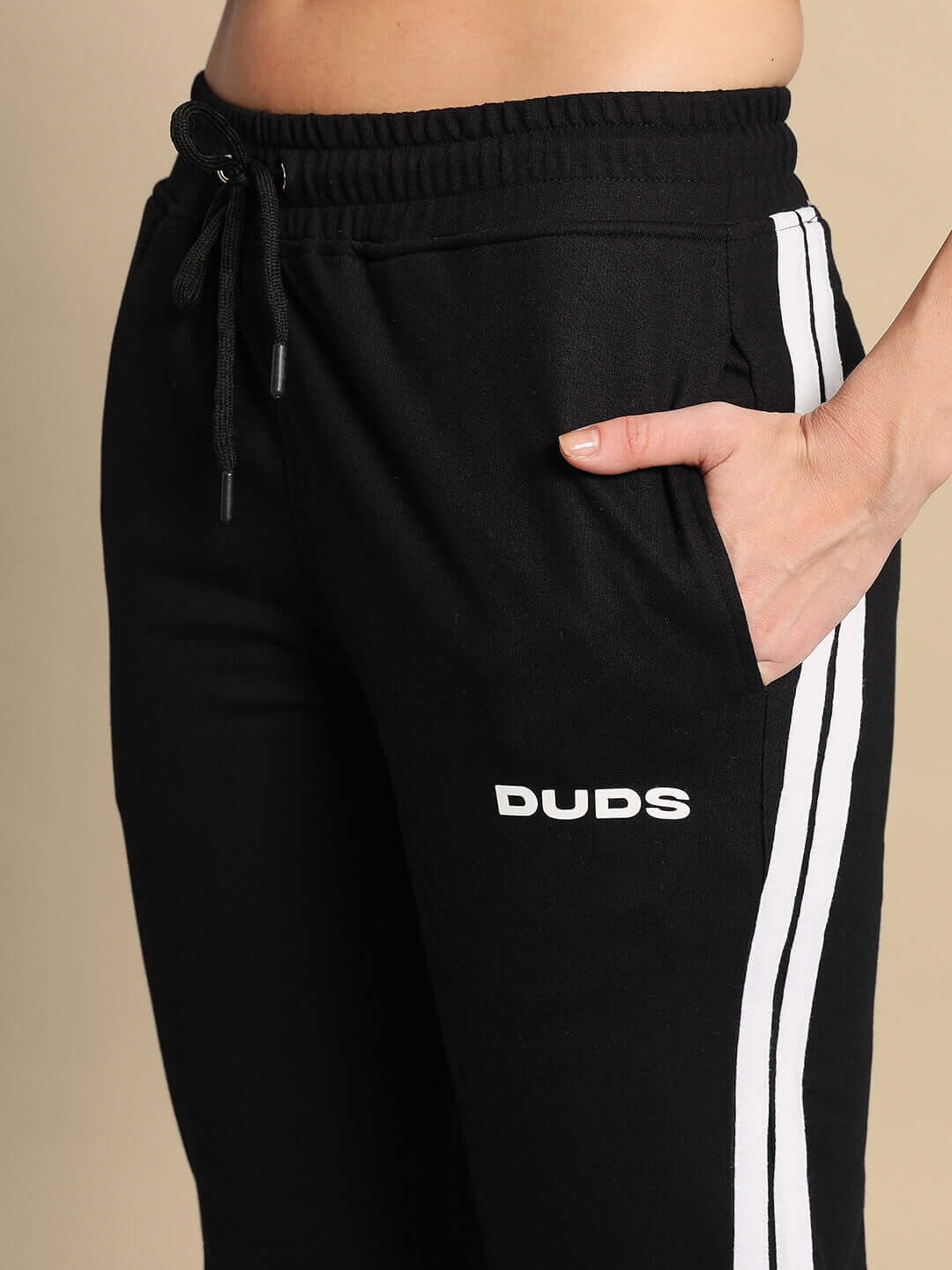 Close-up of Women's Tornado Joggers in Black Red with DUDS logo, highlighting side stripes and hand in pocket.