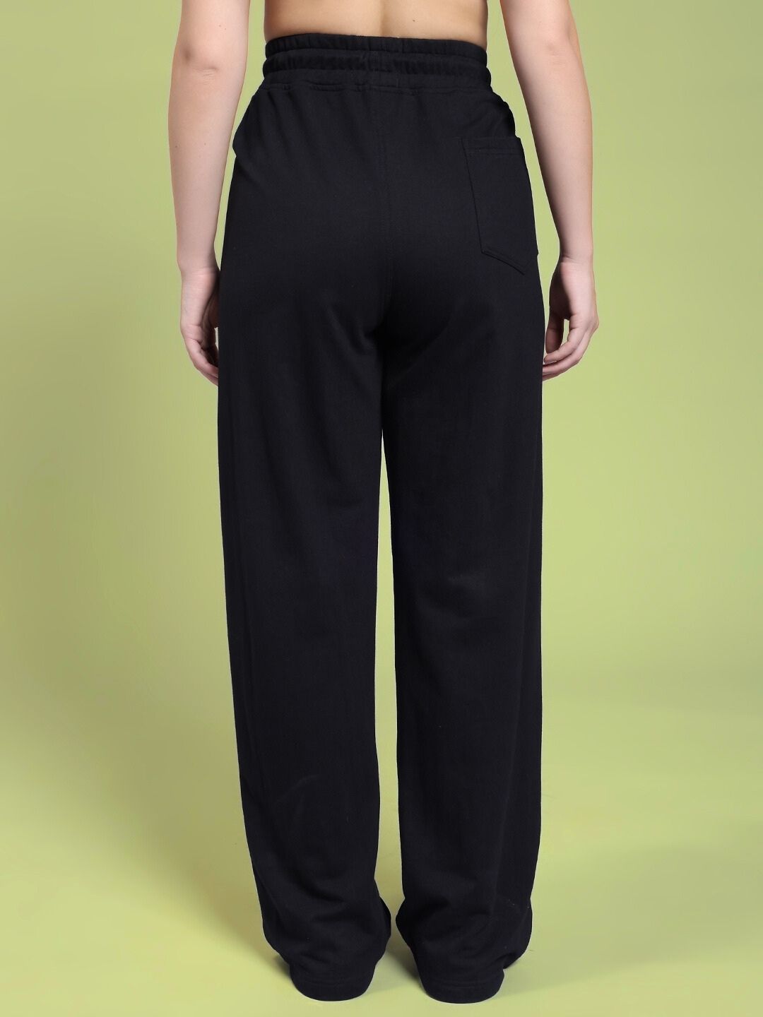 Back view of WOMEN RIFT RELAXED FIT JOGGER IN BLACK showcasing relaxed silhouette and premium fabric on green background.