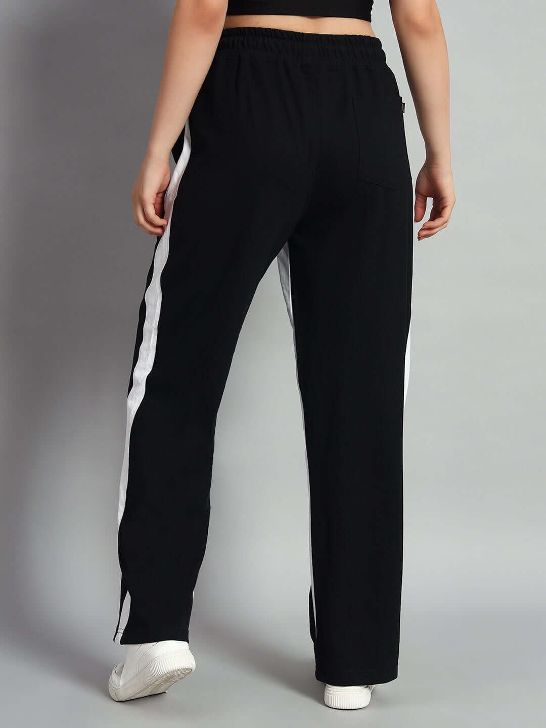 Back view of black women's side seam baggy joggers with white stripes, showcasing a relaxed fit.