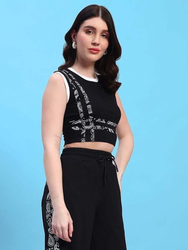 Woman wearing a black Squaro designer crop-top made of premium cotton French terry lycra with patterned detailing, against blue background.