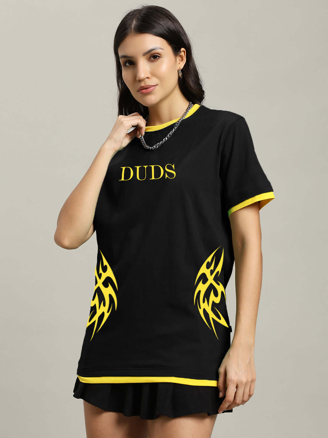 Woman wearing a black t-shirt with yellow trim and graphic design, featuring 'DUDS' text and vibrant flame patterns.
