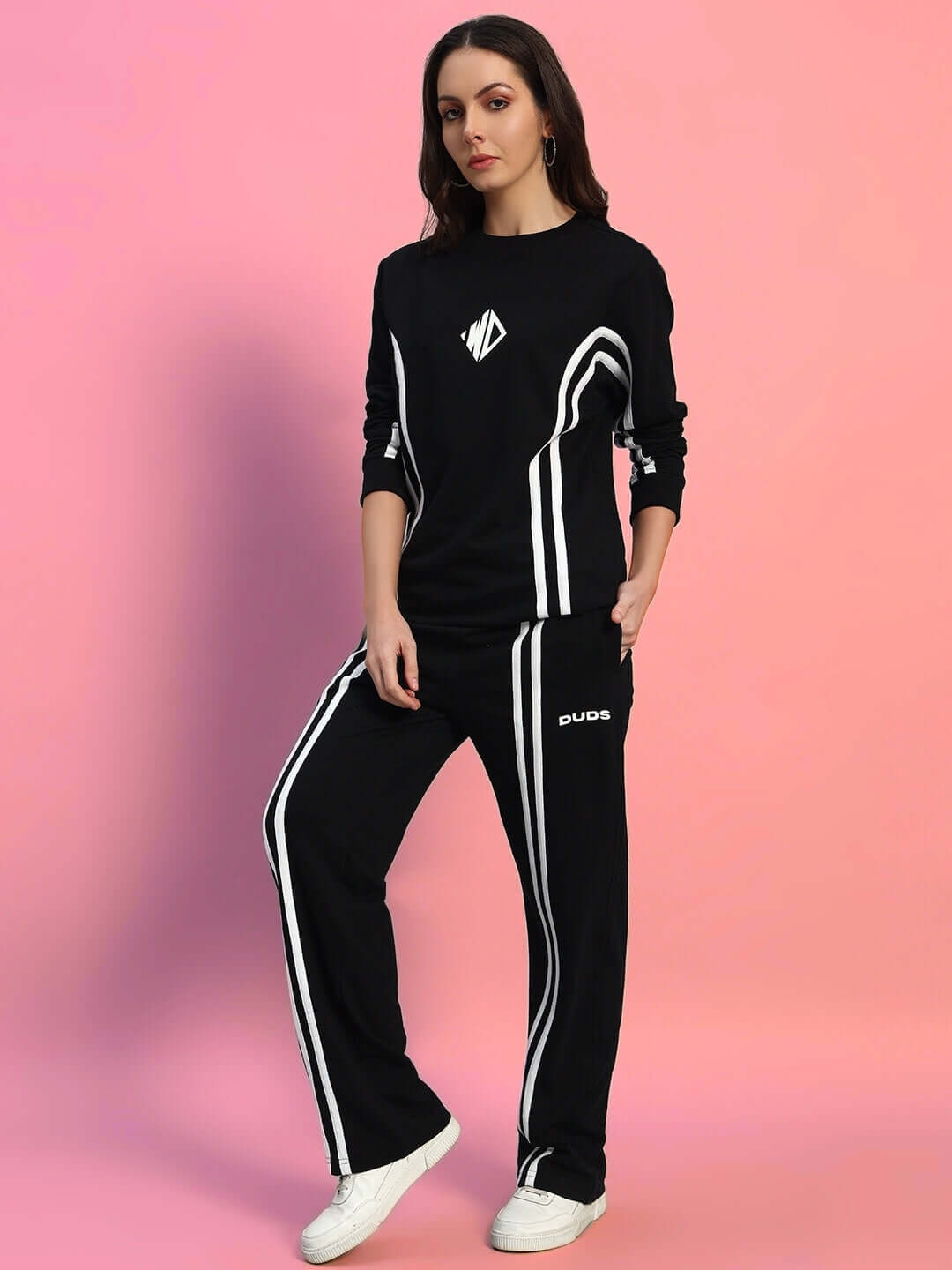 Model wearing WOMEN'S OUTLOOK CO-ORD SET BLACK WITH WHITE STRIPE, showcasing sleek street style against a pink background.