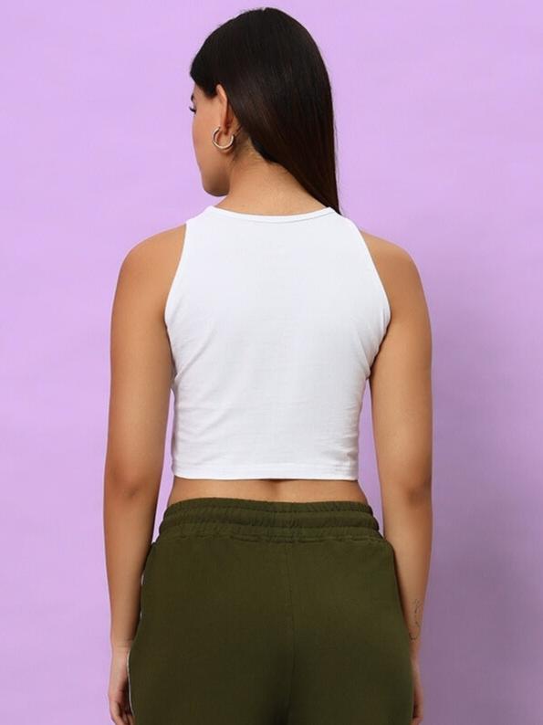Back view of WOMEN BLINK COTTON CROP-TOP WHITE with model wearing green pants against a purple background.