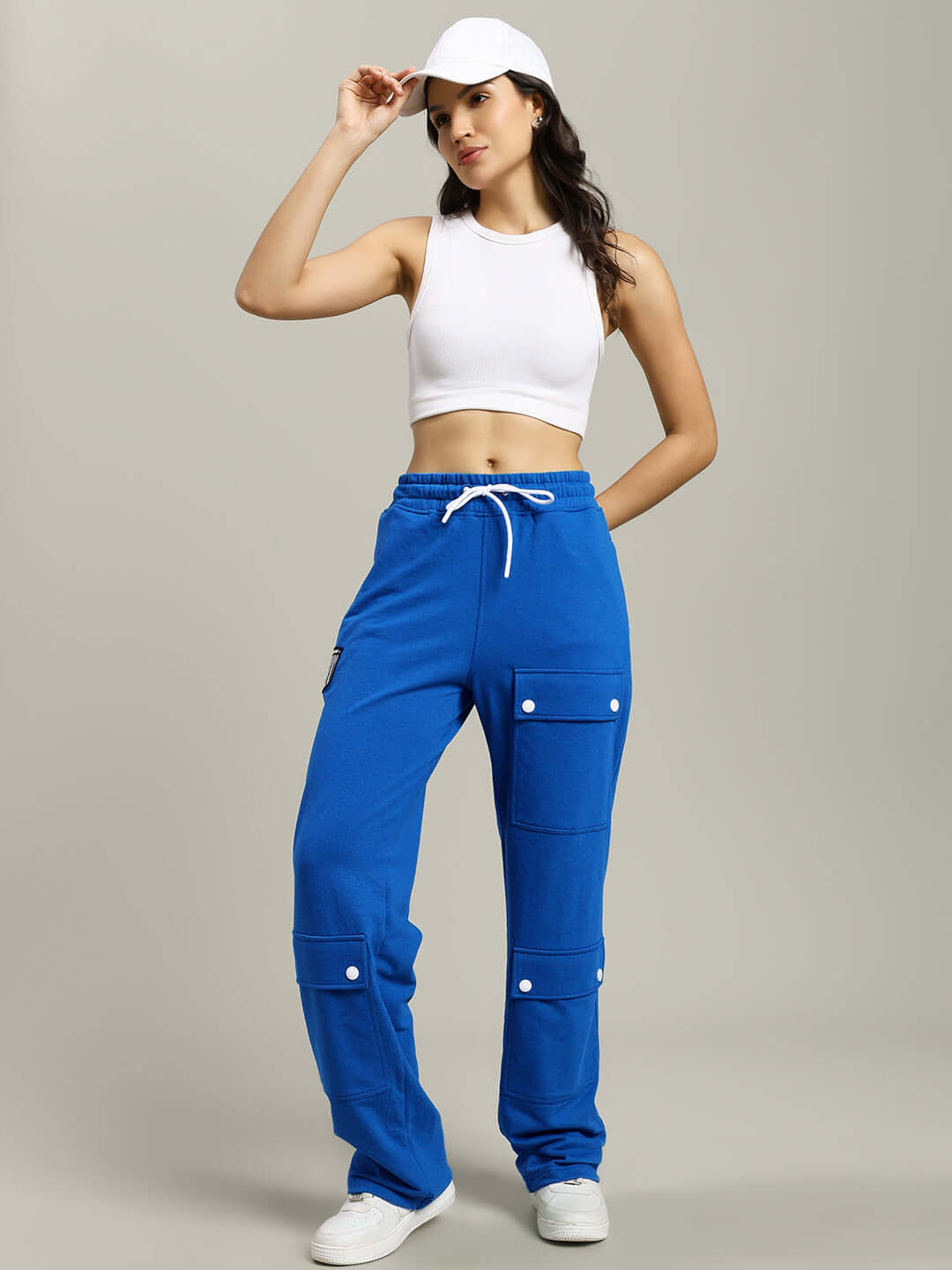 Woman wearing blue flap pocket baggy jogger pants with white crop top and cap