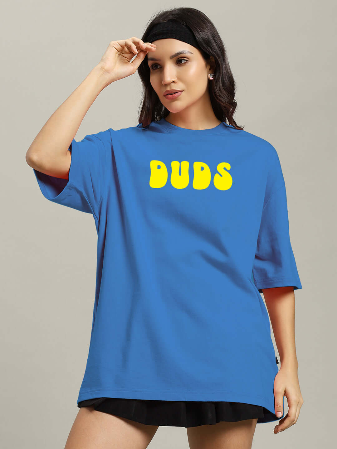 Woman wearing blue oversized t-shirt with yellow 'DUDS' print, made of premium cotton and elastane, featuring French Terry fabric.