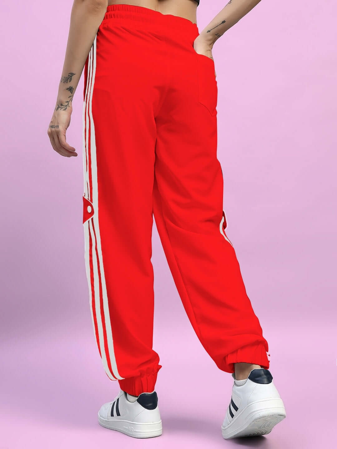 Rear view of women's red relaxed-fit joggers with stripes, styled with white sneakers, ideal for comfortable and trendy wear.