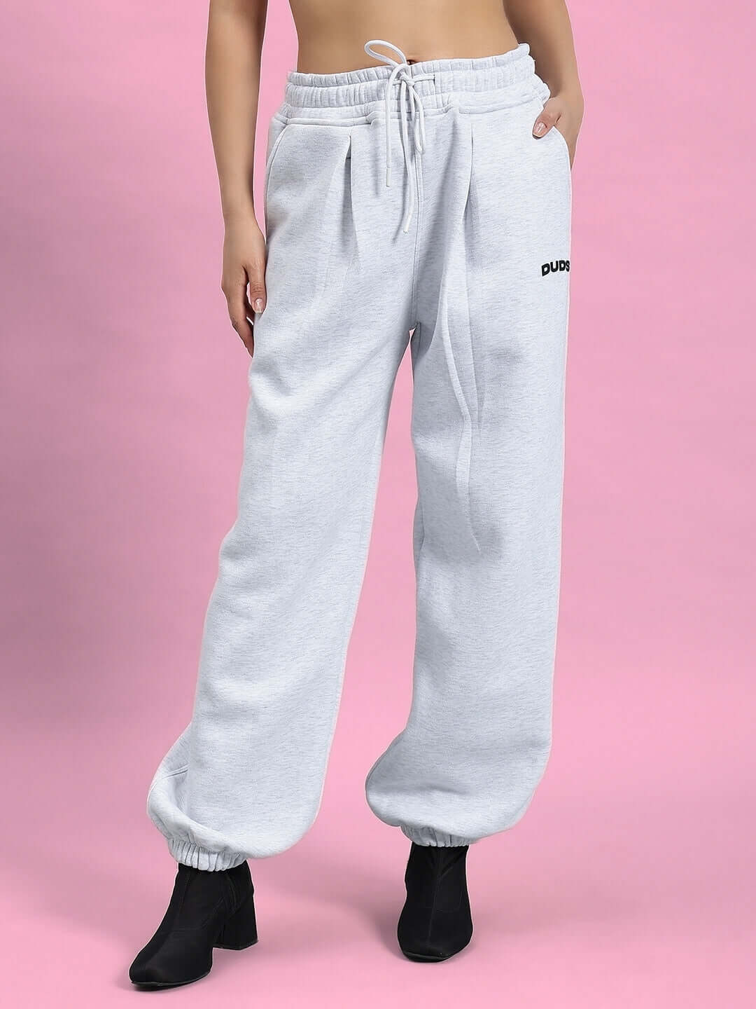 Model wearing WOMEN BONAFIDE FLEECE CO-ORD MELANGE GREY with ribbed cuffs and waistband, showcasing a relaxed fit against a pink background.