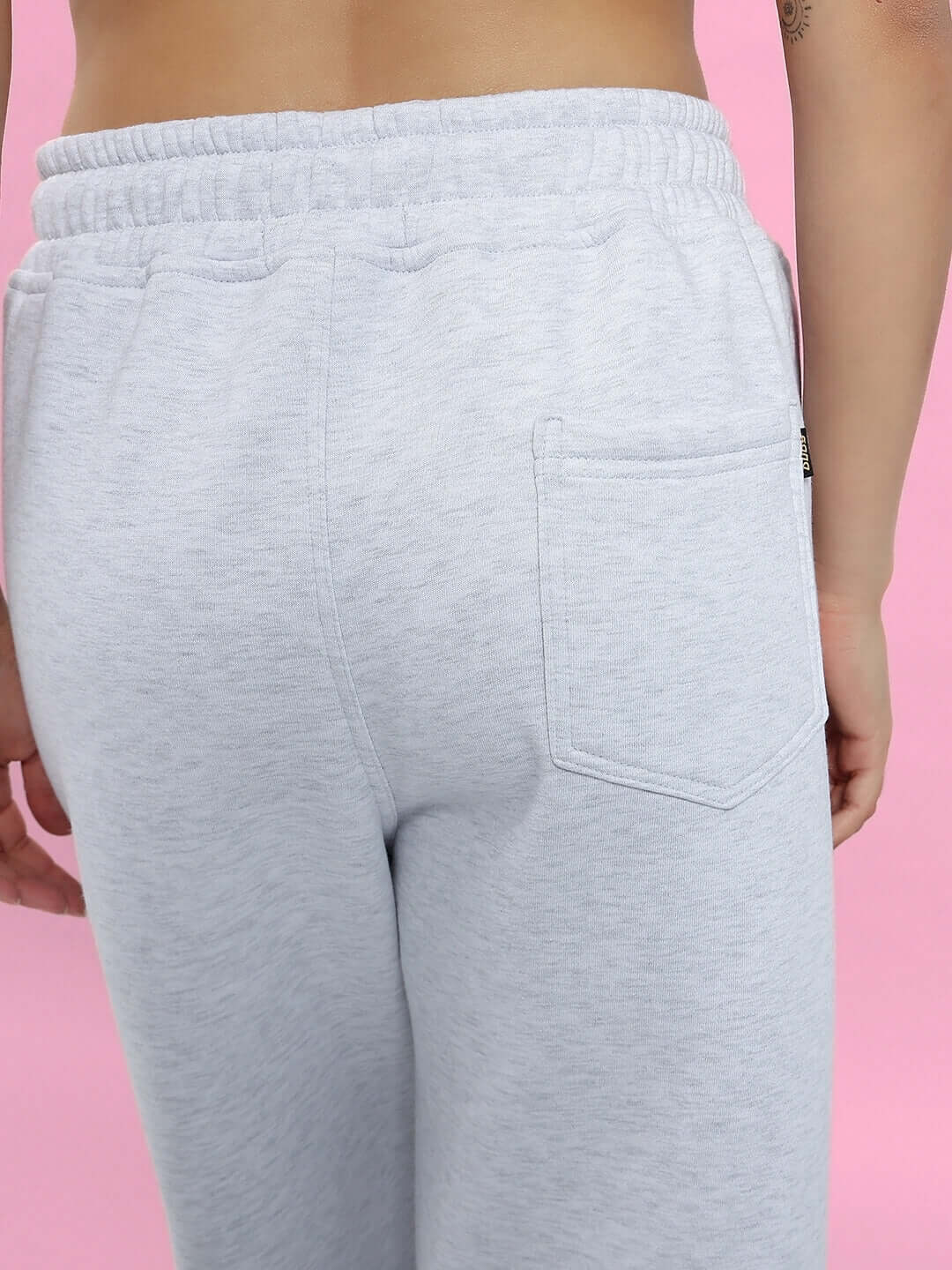 Back view of Women's Bona-Fide Fleece Pant in melange grey, featuring an elastic waistband and pocket, against a pink background.
