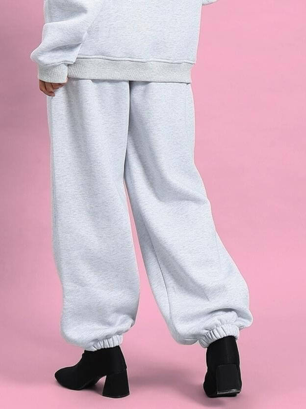 Women's Bona-Fide Fleece Pant Melange Grey, elastic cuffs, paired with black heels, on a pink backdrop.