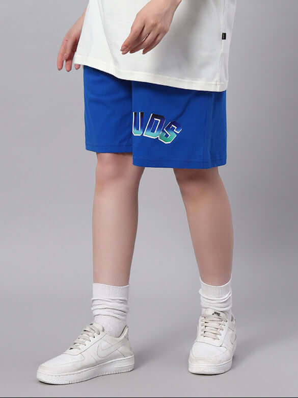 Woman wearing WOMENS BUNNY BUGS SUMMER SHORTS BLUE with bunny design, casual white shoes, showcasing playful summer style.