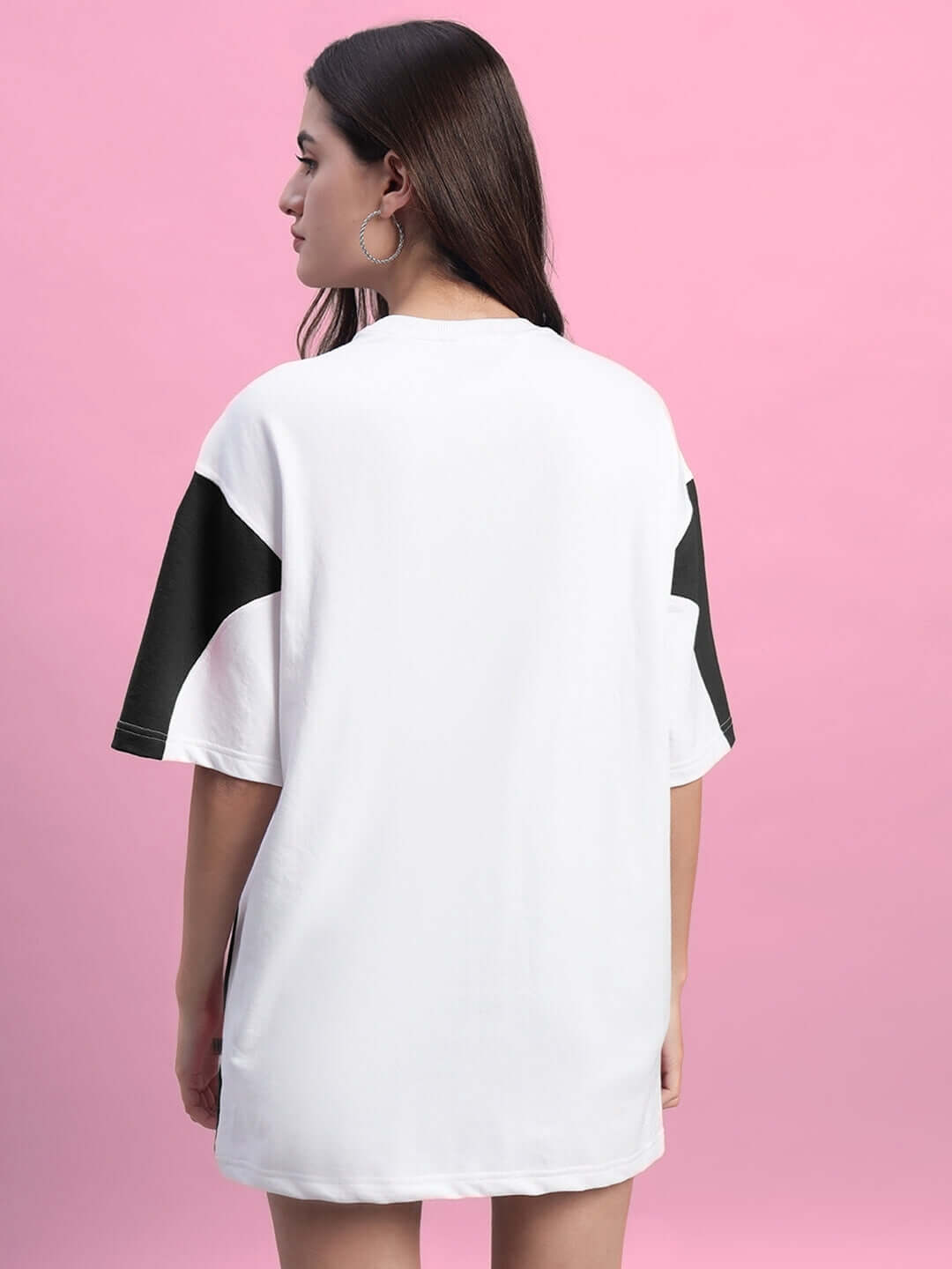 Women's oversized t-shirt in white and black with premium cotton fabric, back view against pink background. Fashionable and comfortable.