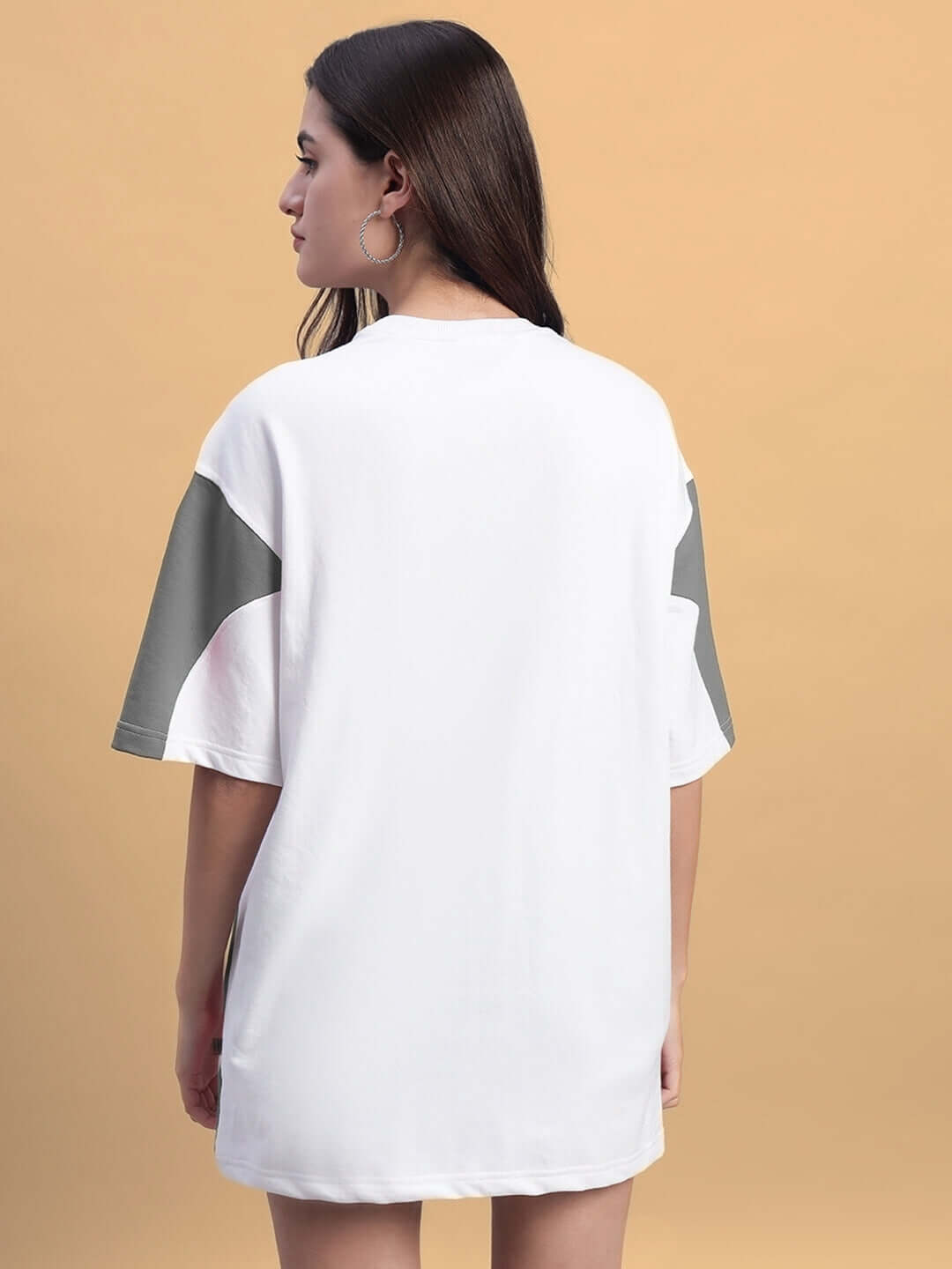 Back view of a woman wearing a women's oversized white grey t-shirt made of premium cotton fabric, showcasing casual comfort and style.