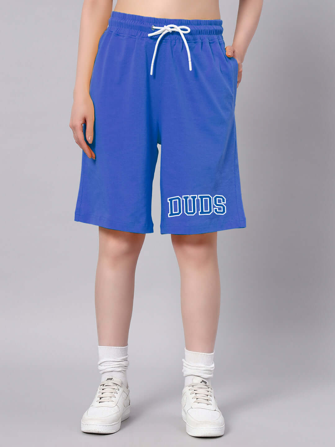 Person wearing DUDS blue shorts, showcasing casual sporty summer style against a neutral background.