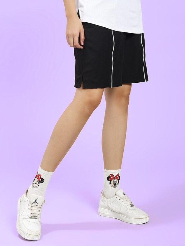 Model wearing WOMEN CHAMPION ZONE FRONT PLATED SHORTS BLACK with white sneakers on purple background.