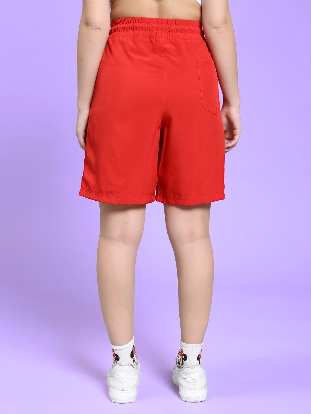 Back view of WOMEN'S CHAMPION ZONE FRONT PLATED SHORTS RED styled with white sneakers and colorful socks.