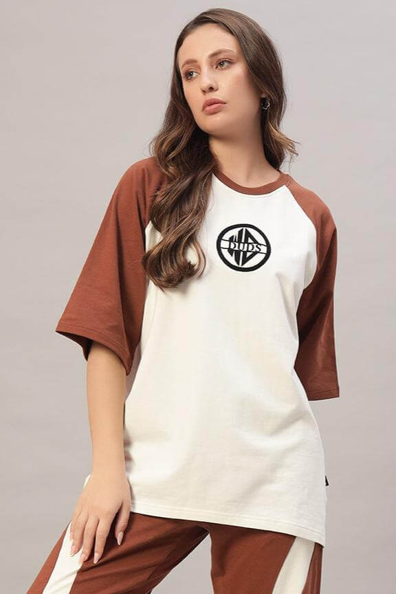 Model wearing a women's chestnut raglan blocked oversized t-shirt in off white and brown, made of premium cotton and elastane.