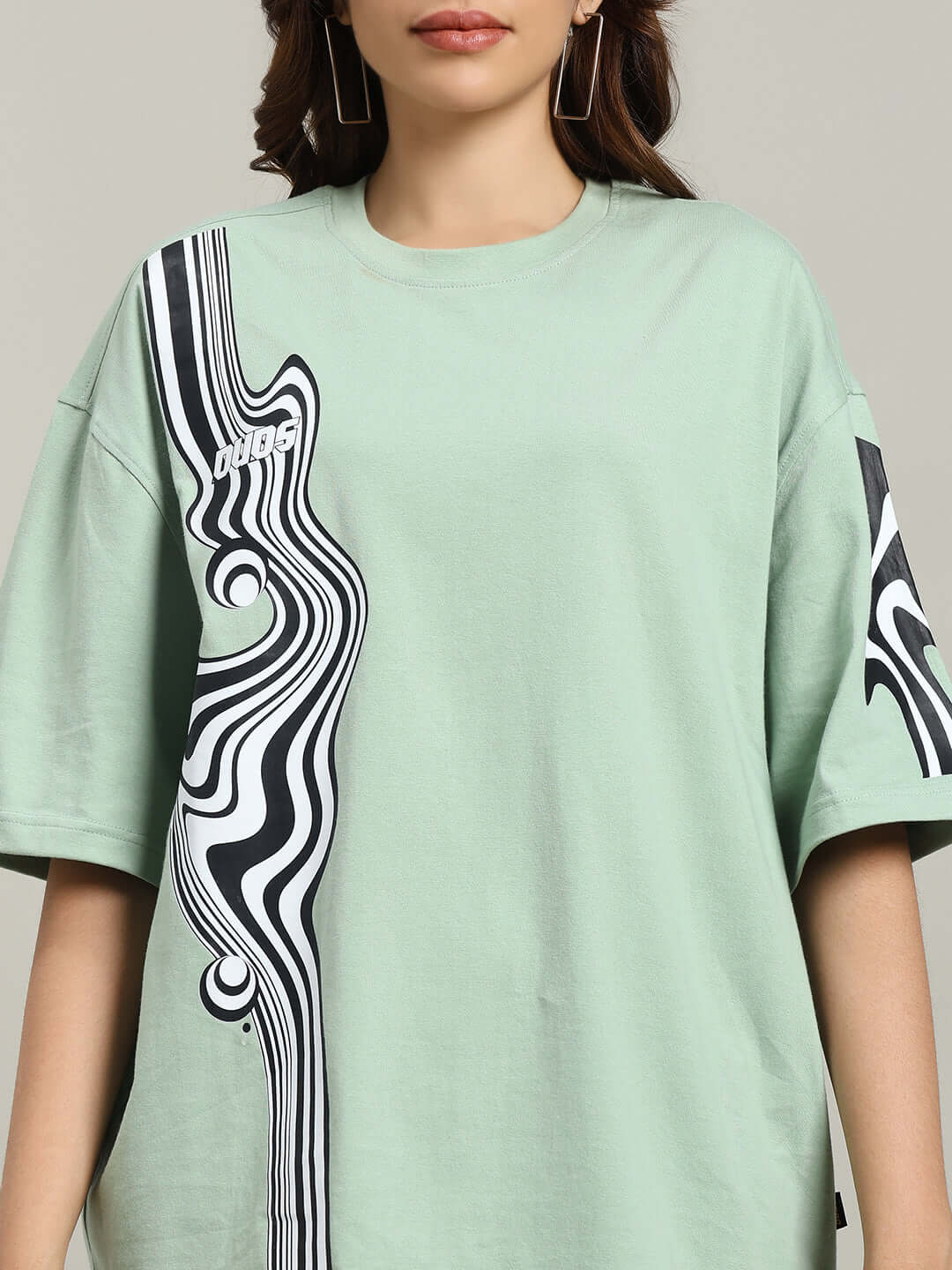 Woman wearing oversized Nyanza Green t-shirt with abstract black and white design, made of premium cotton and elastane, by Color By Colours